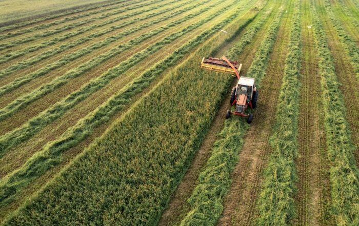 farmer cutting field of grass and alfalfa